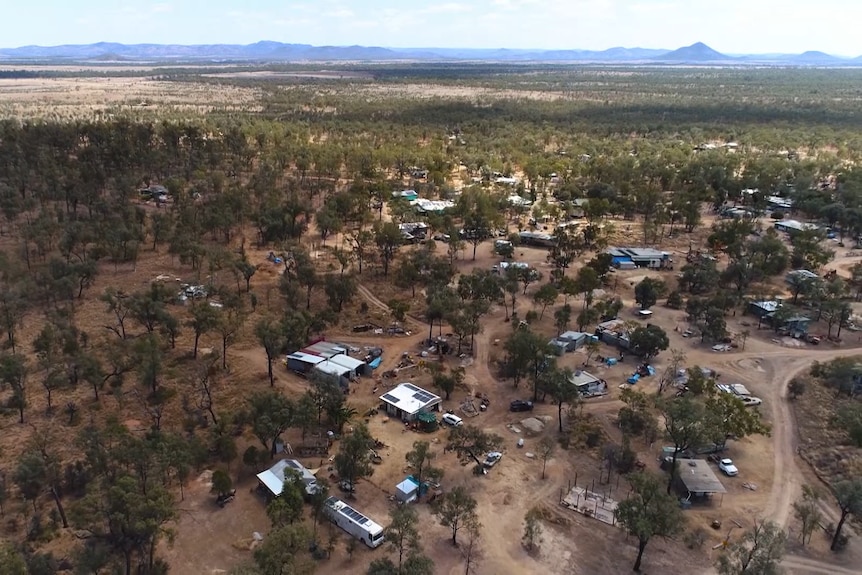 An aerial shot of about a dozen shacks nestled among the red dirt and winding roads